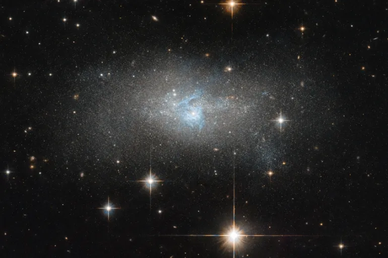 A Hubble Space Telescope image shows bright blue gas threading through galaxy IC 4870, located 28 million light-years away from Earth